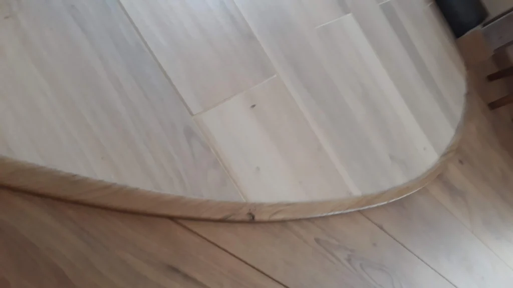 Finition de sol avec barre de seuil courbe en chêne massif réalisée sur mesure pour une transition de parquet à Angers par Garcia Rénovation.