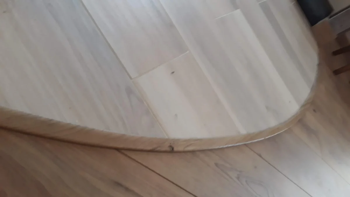 Finition de sol avec barre de seuil courbe en chêne massif réalisée sur mesure pour une transition de parquet à Angers par Garcia Rénovation.