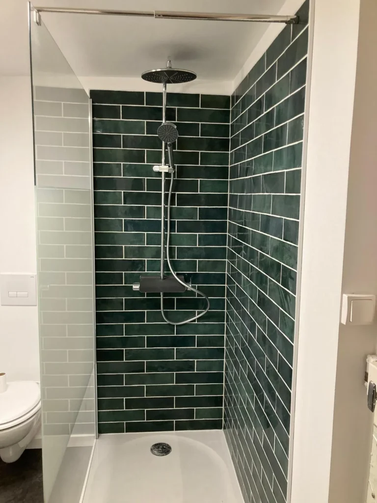 Rénovation de salle de bain à Angers : pose de faïence murale verte type zellige et colonne de douche moderne par Garcia Rénovation.