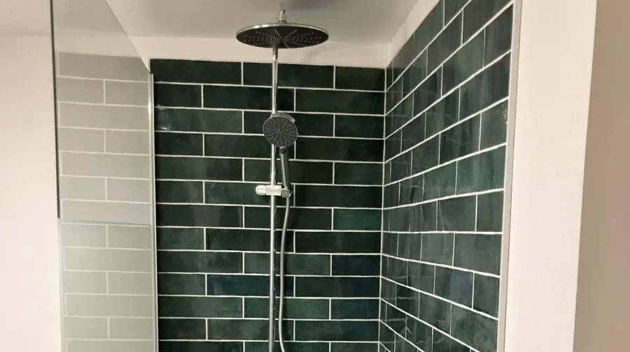 Rénovation de salle de bain à Angers : pose de faïence murale verte type zellige et colonne de douche moderne par Garcia Rénovation.