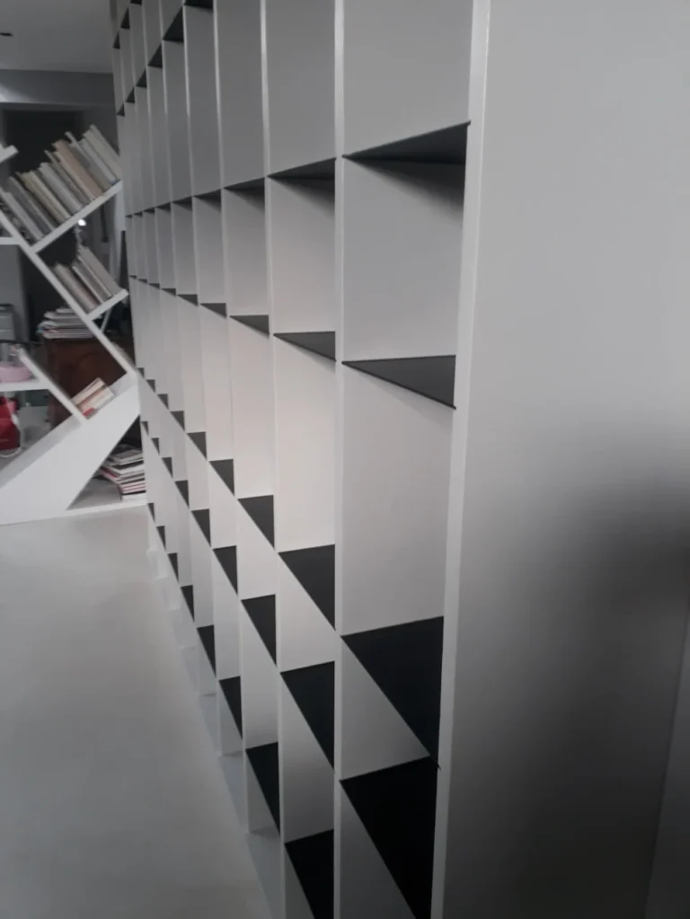 Aménagement d'un rangement sur mesure avec structure géométrique suspendue et bibliothèque sous escalier réalisé à Angers par Garcia Rénovation.