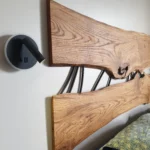 Détail d'une tête de lit sur mesure en chêne massif avec bords naturels "live edge" et inserts en métal noir par Garcia Collection.