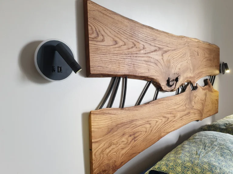 Détail d'une tête de lit sur mesure en chêne massif avec bords naturels "live edge" et inserts en métal noir par Garcia Collection.