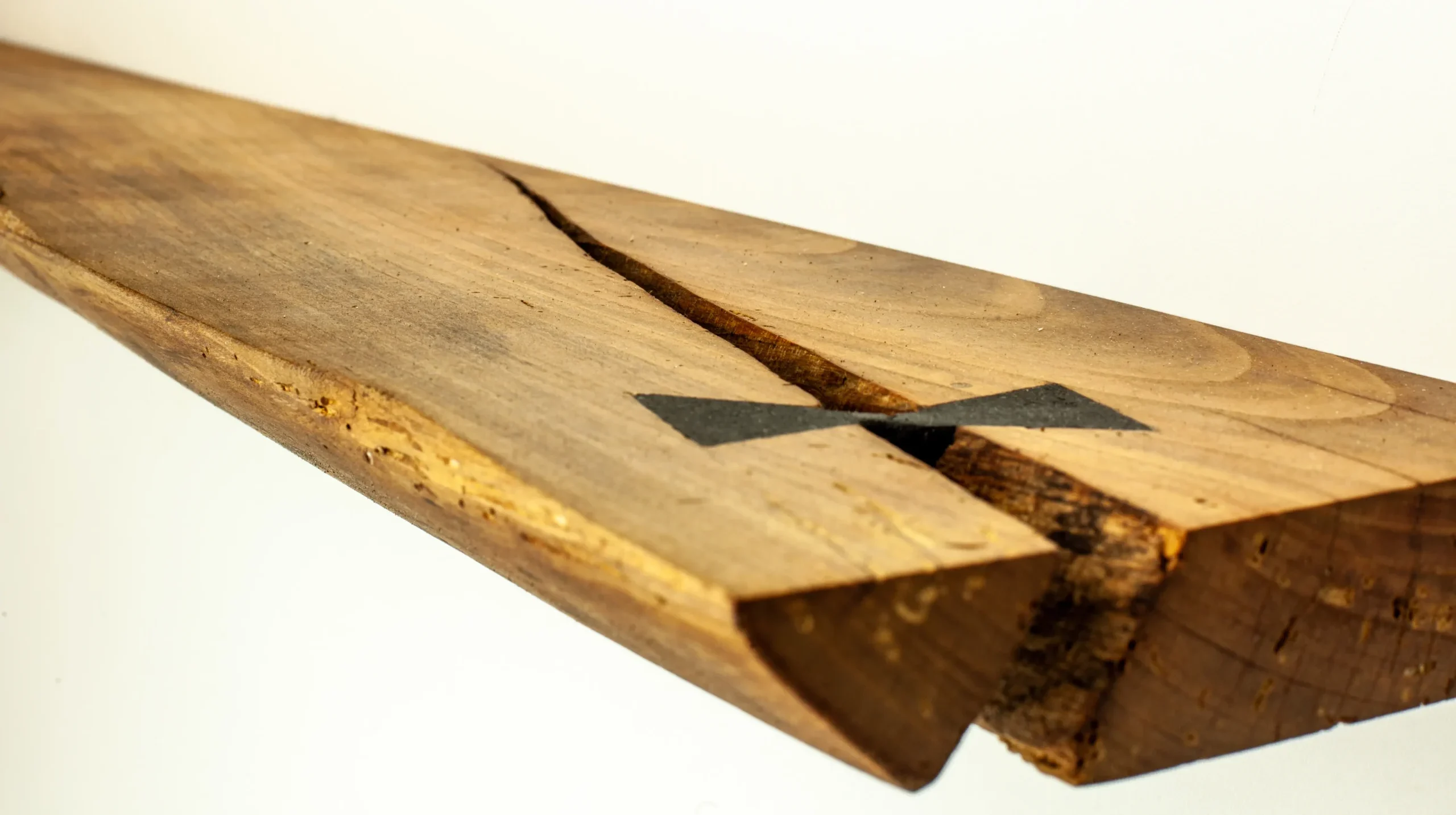 Détail technique d'une incrustation en nœud papillon (butterfly key) pour la stabilisation d'une fissure sur un plateau en bois massif par Garcia Collection.