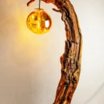 Lampe sculpture monumentale en bois brut noueux avec globe lumineux ambré suspendu, pièce unique Garcia Collection.