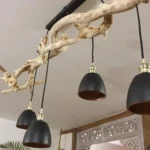 Luminaire suspendu design créé à partir d'une branche de bois flotté avec quatre abats-jours noirs, création Garcia Collection.