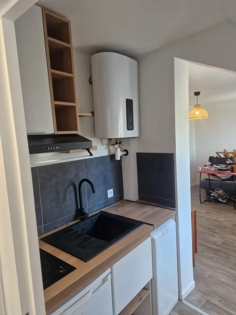Rénovation complète d'une petite cuisine moderne avec plan de travail bois et crédence sombre à Angers.
