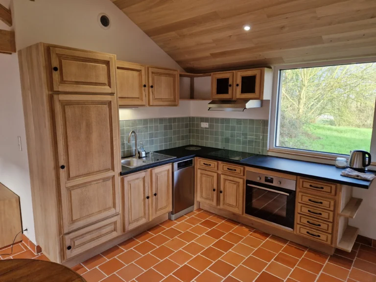 Rénovation de cuisine rustique chic avec meubles en bois massif sur mesure, crédence en zellige vert et plafond rampant en bois à Angers.