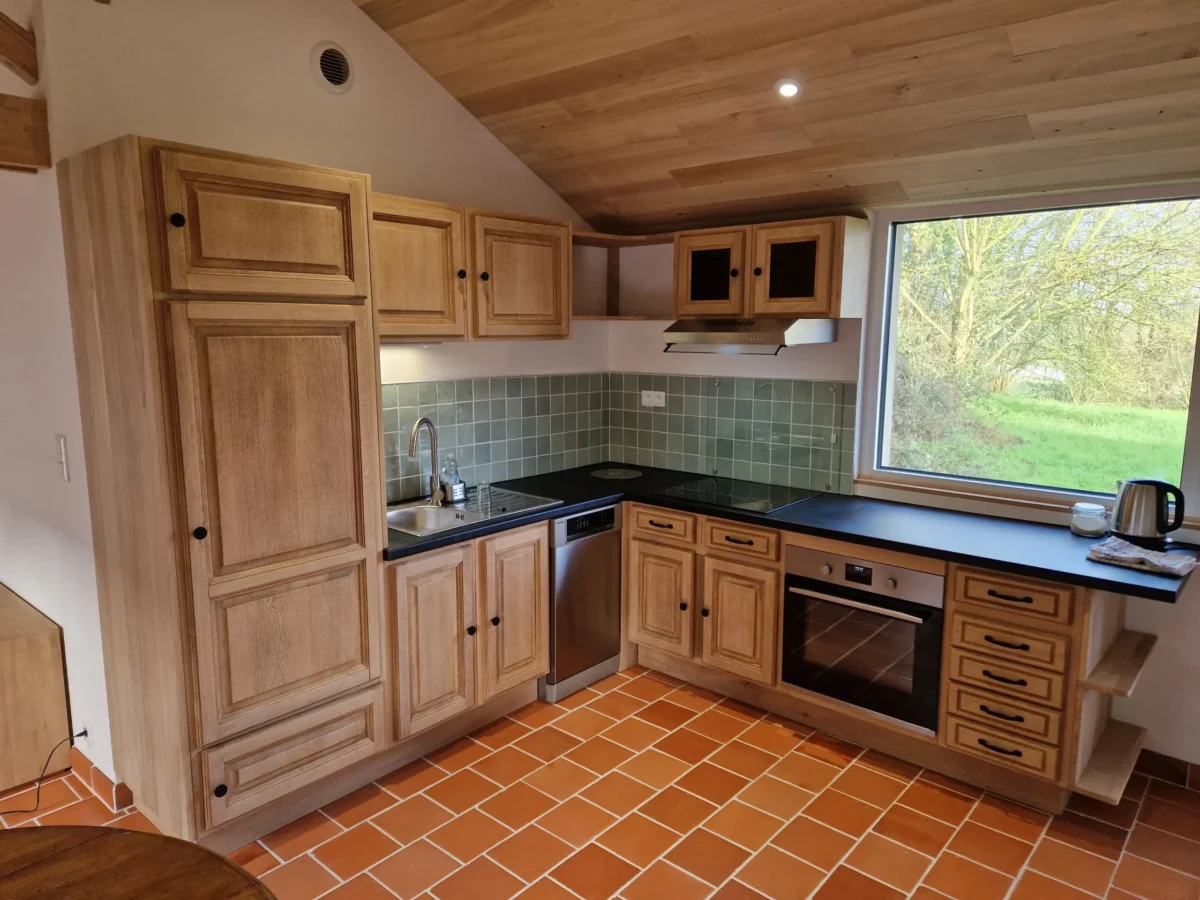 Rénovation de cuisine rustique chic avec meubles en bois massif sur mesure, crédence en zellige vert et plafond rampant en bois à Angers.
