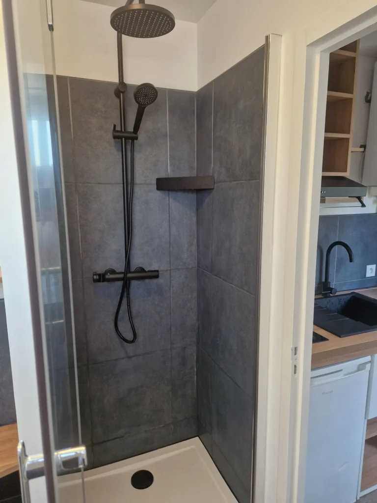 Rénovation de douche moderne avec carrelage anthracite grand format et robinetterie noire mate, Garcia Rénovation Angers.
