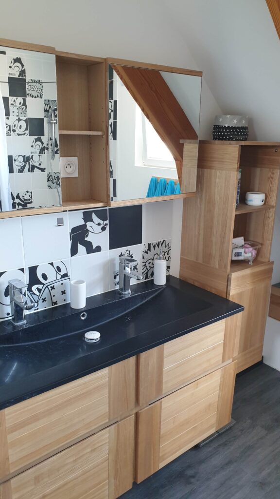 Salle de bain avec double vasque noire, faïence graphique noir et blanc et meuble en bois